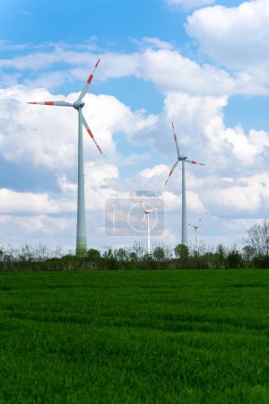 Foto de Un disparo vertical de turbinas eólicas en un campo verde bajo un cielo azul con nubes. - Imagen libre de derechos