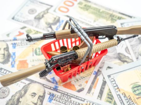 Téléchargez les photos : Un gros plan de fusils dans un panier rouge au-dessus des billets en dollars américains - en image libre de droit