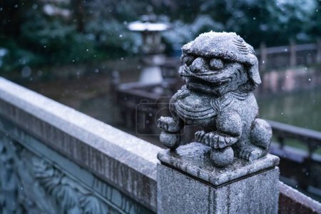 Téléchargez les photos : Un gros plan d'une petite statue asiatique en béton dans un parc lors d'une chute de neige - en image libre de droit