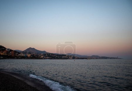 Photo for A scenic evening shot at Santa Amalia beach with a view of buildings and hills in front of a sea - Royalty Free Image