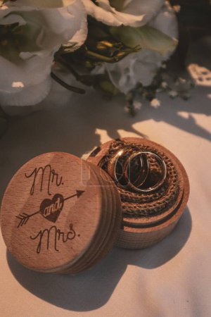 Photo for A vertical closeup of wedding bands in an adorable wooden box - Royalty Free Image