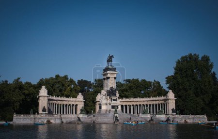 Foto de Un lago y gente en barcas navegando alrededor de un edificio cultural en el Parque El Retiro en Madrid, España - Imagen libre de derechos