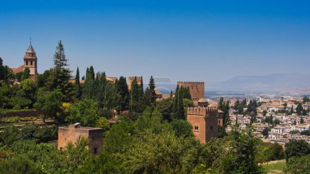 Téléchargez les photos : La vue de Sainte Marie sur l'Alhambra et les tours du palais entourées d'arbres verts. Grenade, Espagne. - en image libre de droit