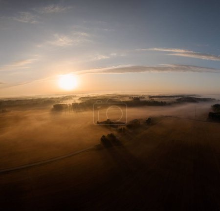 Téléchargez les photos : Une vue aérienne du paysage à peine visible en raison du temps brumeux au coucher du soleil doré - en image libre de droit