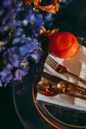 Foto de Una vista superior de una mesa de lujo con una mandarina en un plato rodeado de decoraciones florales, preparativos para una celebración - Imagen libre de derechos