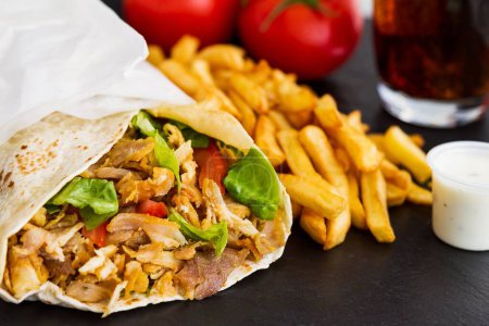 Téléchargez les photos : Un gros plan de shawarma avec côté frites sur fond noir - en image libre de droit