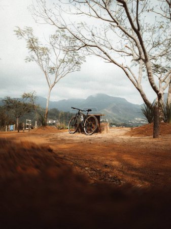 Photo for A vertical shot of a bicycle next to a wooden table with mountains in the background - Royalty Free Image