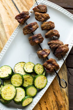 Téléchargez les photos : Un gros plan d'un steak Shish Kababb avec un plat d'accompagnement de courgettes grillées - en image libre de droit