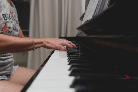 Téléchargez les photos : Belle pianiste brésilienne touchant des touches de piano, jouant du piano droit. Concept enseignement de la musique et des arts. Détendez-vous et joyeux. - en image libre de droit
