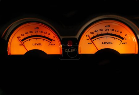 Foto de Medidor de decibelios de un amplificador de sonido iluminado naranja sobre fondo negro - Imagen libre de derechos