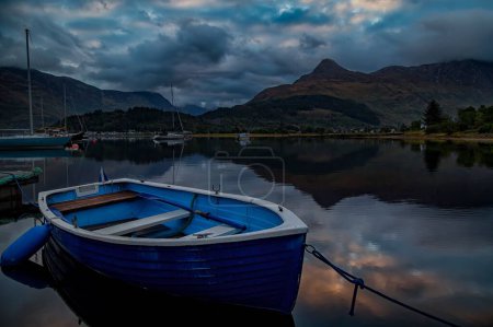 Téléchargez les photos : Un bateau à rames sur l'eau en Écosse, avec des montagnes en arrière-plan par une journée nuageuse - en image libre de droit
