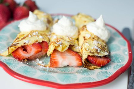 Téléchargez les photos : Assiette avec crêpes aux fraises et garniture à la crème fouettée - en image libre de droit
