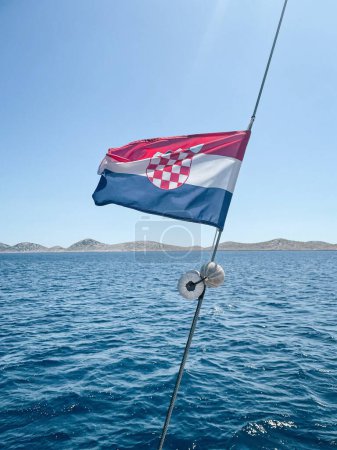 Téléchargez les photos : Plan vertical d'un drapeau croate avec une mer et des montagnes en arrière-plan - en image libre de droit