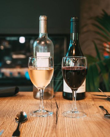 Photo for A vertical shot of the glasses of red and white wine before the bottles - Royalty Free Image