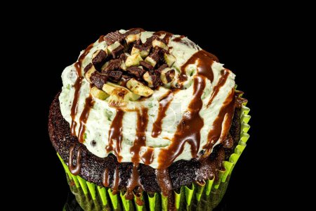 Photo for A closeup shot of a homemade baked cupcake placed on a black reflective surface - Royalty Free Image