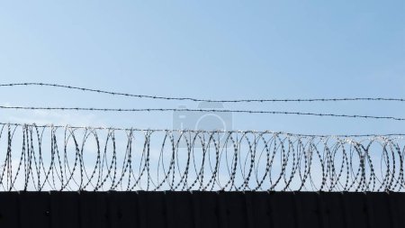 Téléchargez les photos : Une clôture en fil de fer barbelé avec ciel sur le fond - en image libre de droit