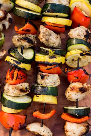 Photo for A vertical shot of grilled vegetable and chicken kabobs on a wooden plate - Royalty Free Image