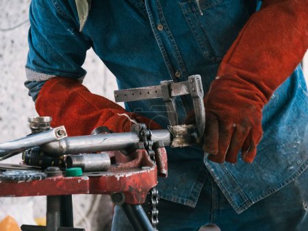 Téléchargez les photos : Gros plan d'un homme portant des gants travaillant sur des équipements métalliques - le concept de production de métaux artisanaux - en image libre de droit