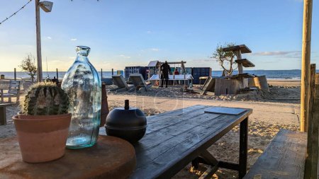 Téléchargez les photos : Une table avec bouteille en verre et cactus en arrière-plan de la mer - en image libre de droit