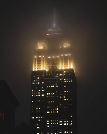Téléchargez les photos : Une vue rapprochée de l'Empire State Building à New York pendant une nuit brumeuse - en image libre de droit