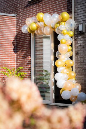 Téléchargez les photos : Un plan vertical de décorations de mariage sur la porte d'une maison de village avec rubans et ballons - en image libre de droit