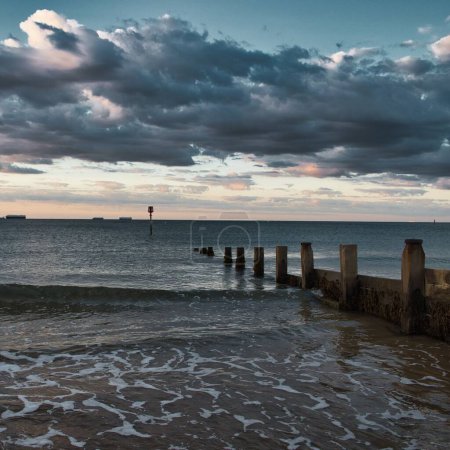 Téléchargez les photos : Paysage nuageux sombre sur la mer ondulée avec brise-lames, Île de Wight, Angleterre - en image libre de droit