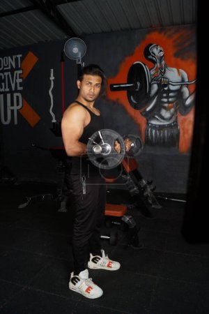 Photo for A vertical shot of the South Asian man doing biceps lifting in the gym - Royalty Free Image