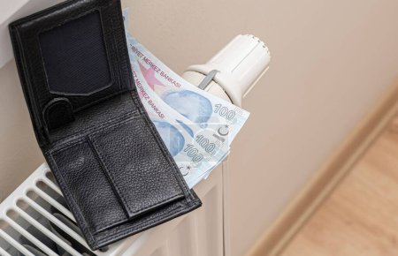 Téléchargez les photos : Un portefeuille et des billets en lires turques sur radiateur de chauffage concept de coûts de chauffage coûteux - en image libre de droit