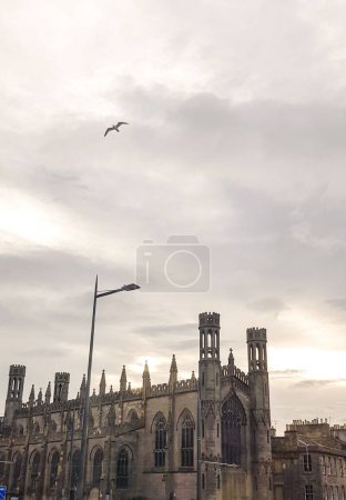 Foto de Un plano vertical de la iglesia de San Pablo y San Jorge con una gaviota volando bajo el cielo gris - Imagen libre de derechos