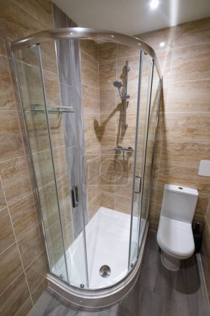 Téléchargez les photos : Une élégante salle de bain moderne avec des murs en tuiles marron lisse et des lumières vives - en image libre de droit