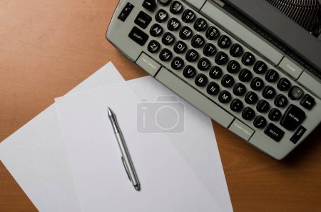 Foto de Un primer plano de una máquina de escribir con papeles en blanco y una pluma. Concepto de escritura. - Imagen libre de derechos