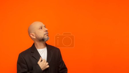 Téléchargez les photos : Portrait d'un homme d'affaires élégant levant les yeux. Isolé sur fond orange. - en image libre de droit