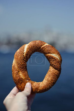 Foto de Un primer plano vertical de una mano sosteniendo un delicioso bagel turco - Imagen libre de derechos