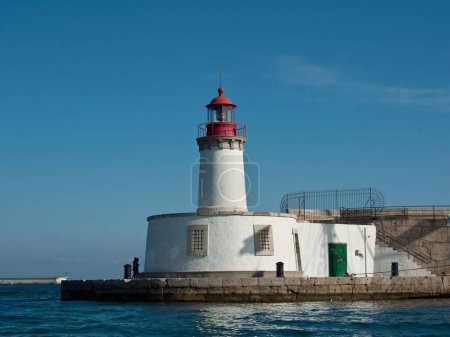 Téléchargez les photos : Une belle journée avec ciel bleu sur la côte méditerranéenne avec phare blanc à Ibiza, Espagne - en image libre de droit