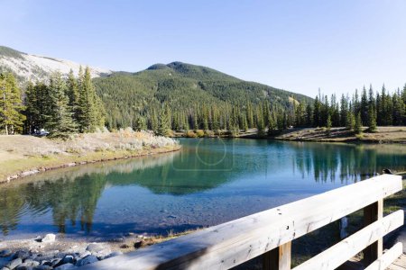 Téléchargez les photos : Un pont en bois au-dessus du ruisseau Bragg avec des montagnes et un ciel bleu en arrière-plan, Canada - en image libre de droit