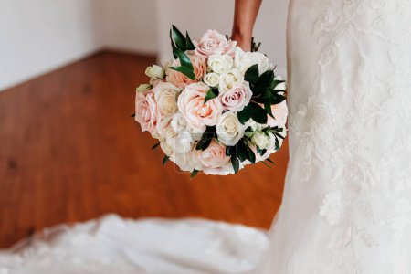 Téléchargez les photos : La mariée dans l'élégante robe blanche tenant le bouquet délicat pendant la cérémonie de mariage - en image libre de droit