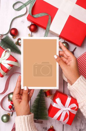 Téléchargez les photos : Un plan vertical d'un cadre vide dans une main féminine sur les décorations de Noël - en image libre de droit