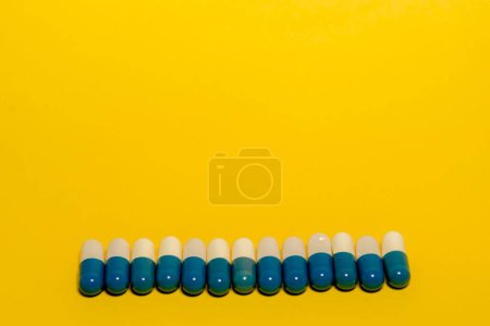 Foto de Un primer plano de píldoras blancas y azules, y medicamentos sobre fondo amarillo - Imagen libre de derechos