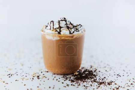 Téléchargez les photos : Gros plan d'un verre de chocolat chaud sur une table, avec de la crème sur le dessus et des morceaux de chocolat sur le côté - en image libre de droit