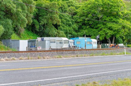 Téléchargez les photos : Une rangée de camping-cars garés dans un camping près de la route et du chemin de fer en Nouvelle-Zélande - en image libre de droit