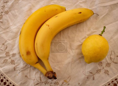 Photo for A closeup of bananas and lemon on textile table sheet - Royalty Free Image