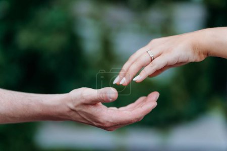 Photo for A female hand with a wedding ring touching the male fingers - Royalty Free Image