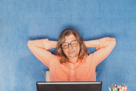 Téléchargez les photos : Une femme heureuse avec ordinateur portable travaillant à la maison ou au bureau - en image libre de droit