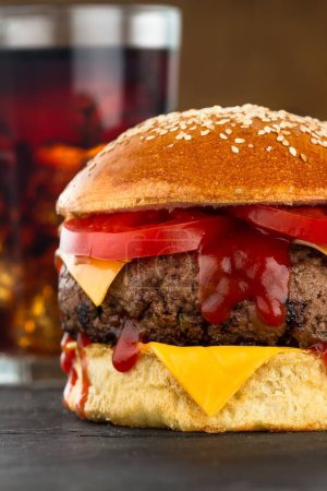 Téléchargez les photos : Un gros plan d'un hamburger sur une tranche de bois et un verre de soda - en image libre de droit