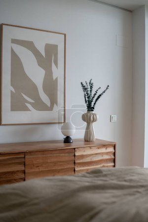 Foto de Una imagen vertical de una habitación, amueblada con una cama, un tocador y una pintura encima de ella - Imagen libre de derechos