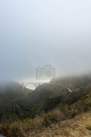 Téléchargez les photos : Un beau cliché d'un pont reliant les montagnes par une journée brumeuse - en image libre de droit
