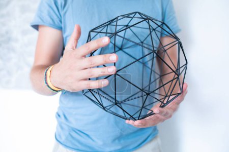 Foto de Un enfoque selectivo de bouclair bola decorativa geométrica en las manos del hombre con fondo borroso - Imagen libre de derechos
