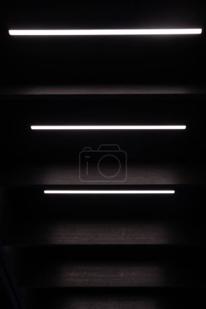Téléchargez les photos : Un plan à angle élevé de l'escalier moderne en bois noir avec des lumières LED blanches - en image libre de droit
