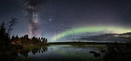Foto de La aurora polar se ilumina en el cielo estrellado sobre el lago en el bosque en Laponia, Finlandia - Imagen libre de derechos