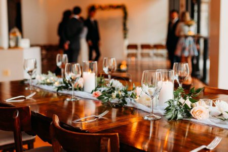 Foto de Una mesa decorada con velas y ramos para la boda con gente en el fondo borroso - Imagen libre de derechos